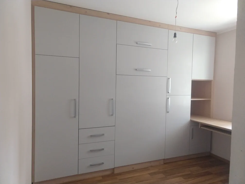 Zamknięte łóżko w szafie z biurkiem i półkami